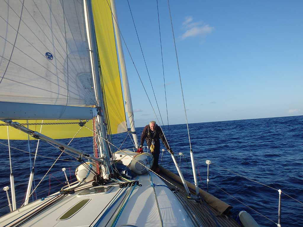 Hoisting the spinnaker. Collective blog comments include, “Watching the big yellow kite pop open as it fills the air and literally lifts the boat forward is living art.” And… “Tough sailing with it in a building sea but man can you move.” And… “The yellow beast is in its cage.”