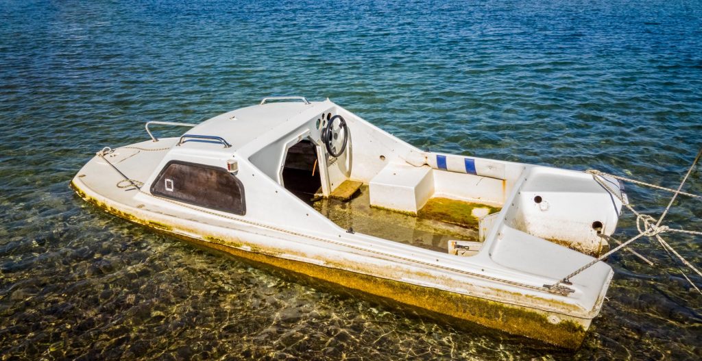 Half-sunk-abandoned-white-boat-floating-on-the-water